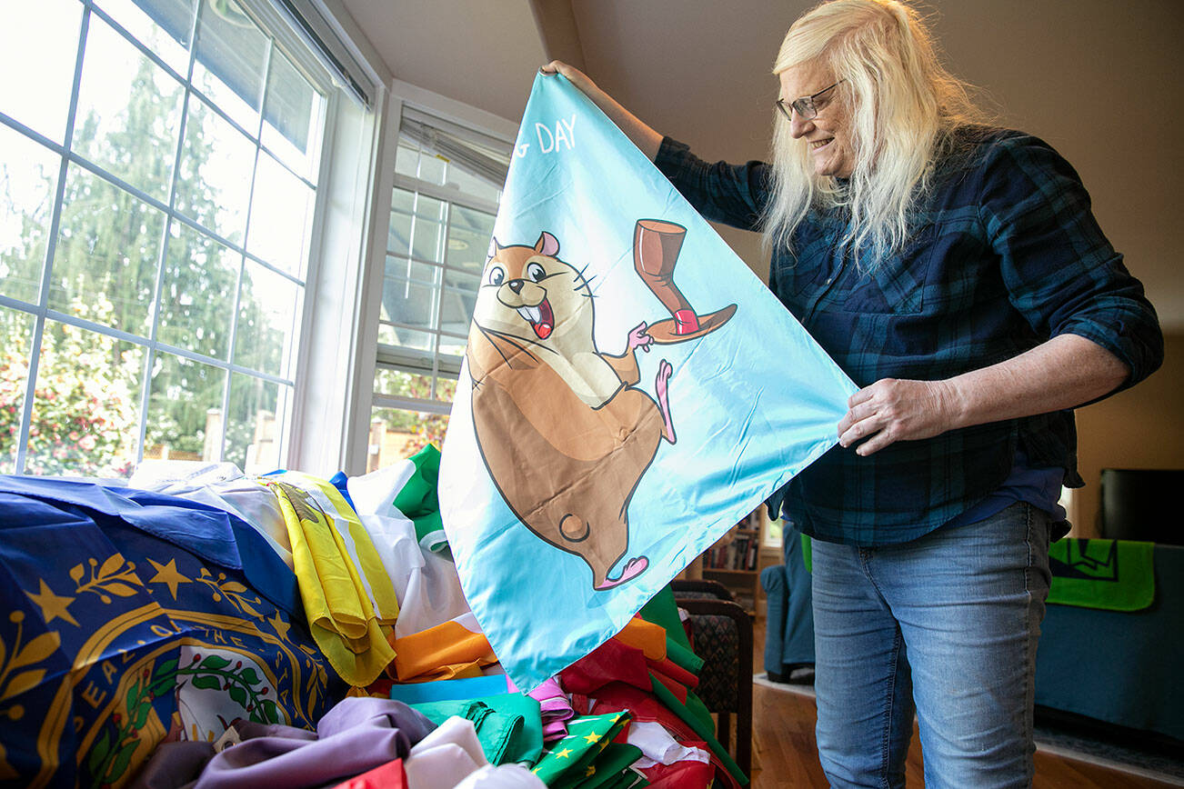 Melissa Batson unfurls a Groundhog Day flag designed by her niece Wednesday, May 11, 2022, at her home in Monroe, Washington. (Ryan Berry / The Herald)