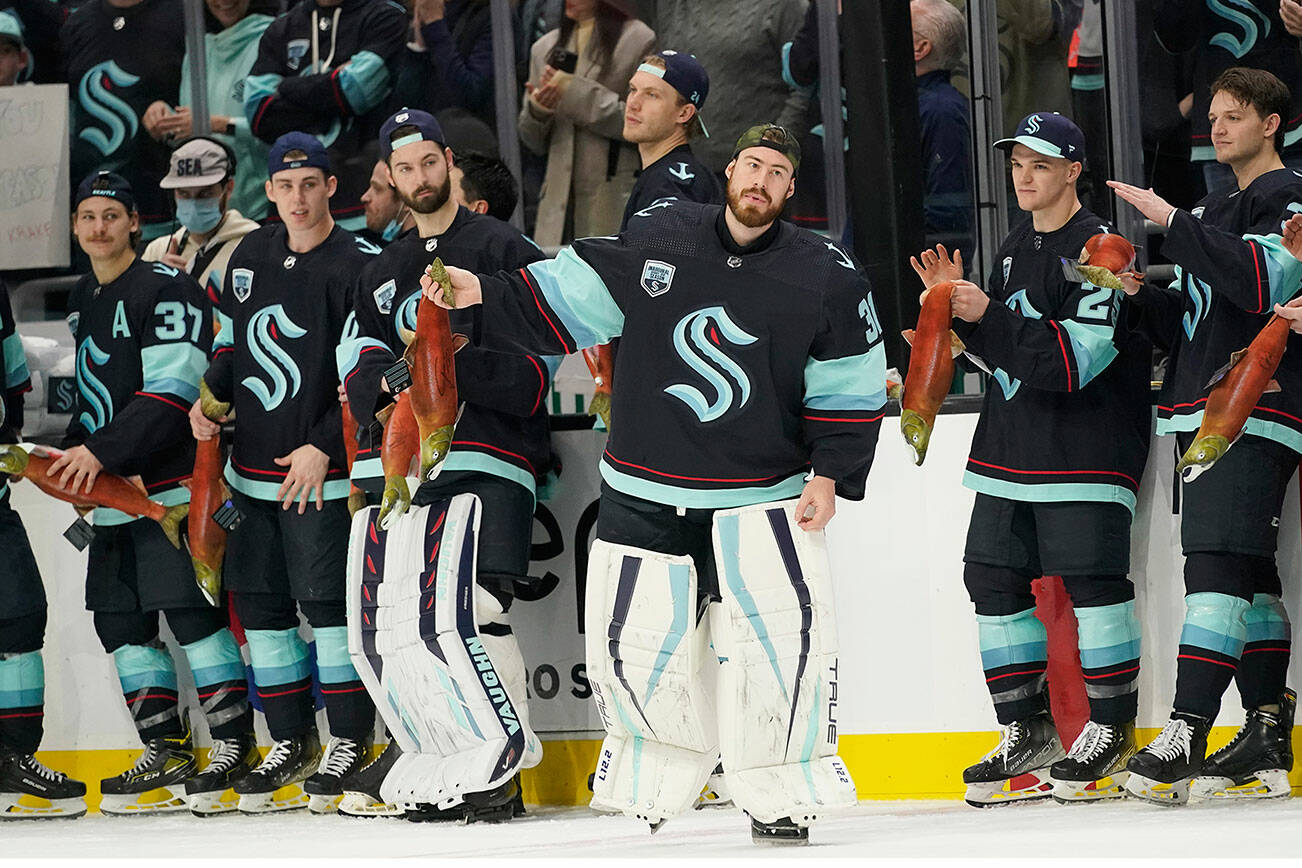 Seattle Kraken goaltender Philipp Grubauer and teammates hold stuffed salmon before tossing them to fans after an NHL hockey game against the San Jose Sharks, Friday, April 29, 2022, in Seattle. The Kraken won 3-0. (AP Photo/Ted S. Warren)
