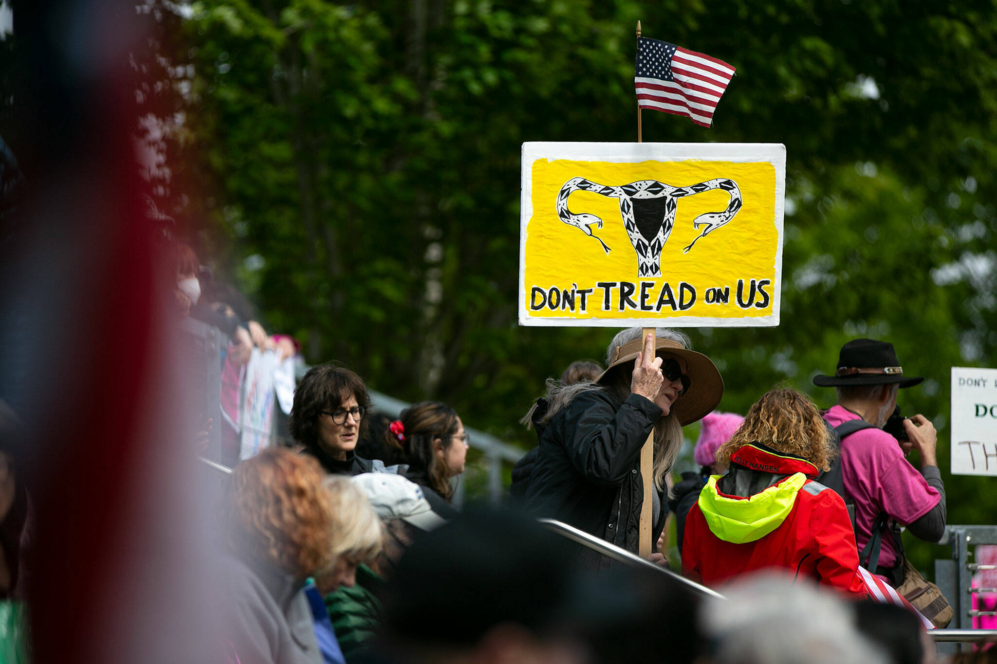 A woman holds a sign that depicts a pro-abortion rights version of the Gadsden flag during Snohomish County’s “Bans Off Our Bodies” rally Saturday, May 14, 2022, outside the county courthouse in Everett, Washington. (Ryan Berry / The Herald)