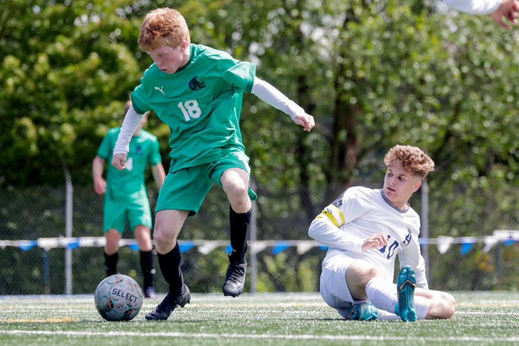 Edmonds-Woodway’s Benjamin Hanson avoids a tackle by Arlington’s Kayden Allen to score a goal in the second half Saturday afternoon at Shoreline Stadium in Shoreline, Washington on May 14, 2022. The Warriors won 4-2. (Kevin Clark / The Herald)
