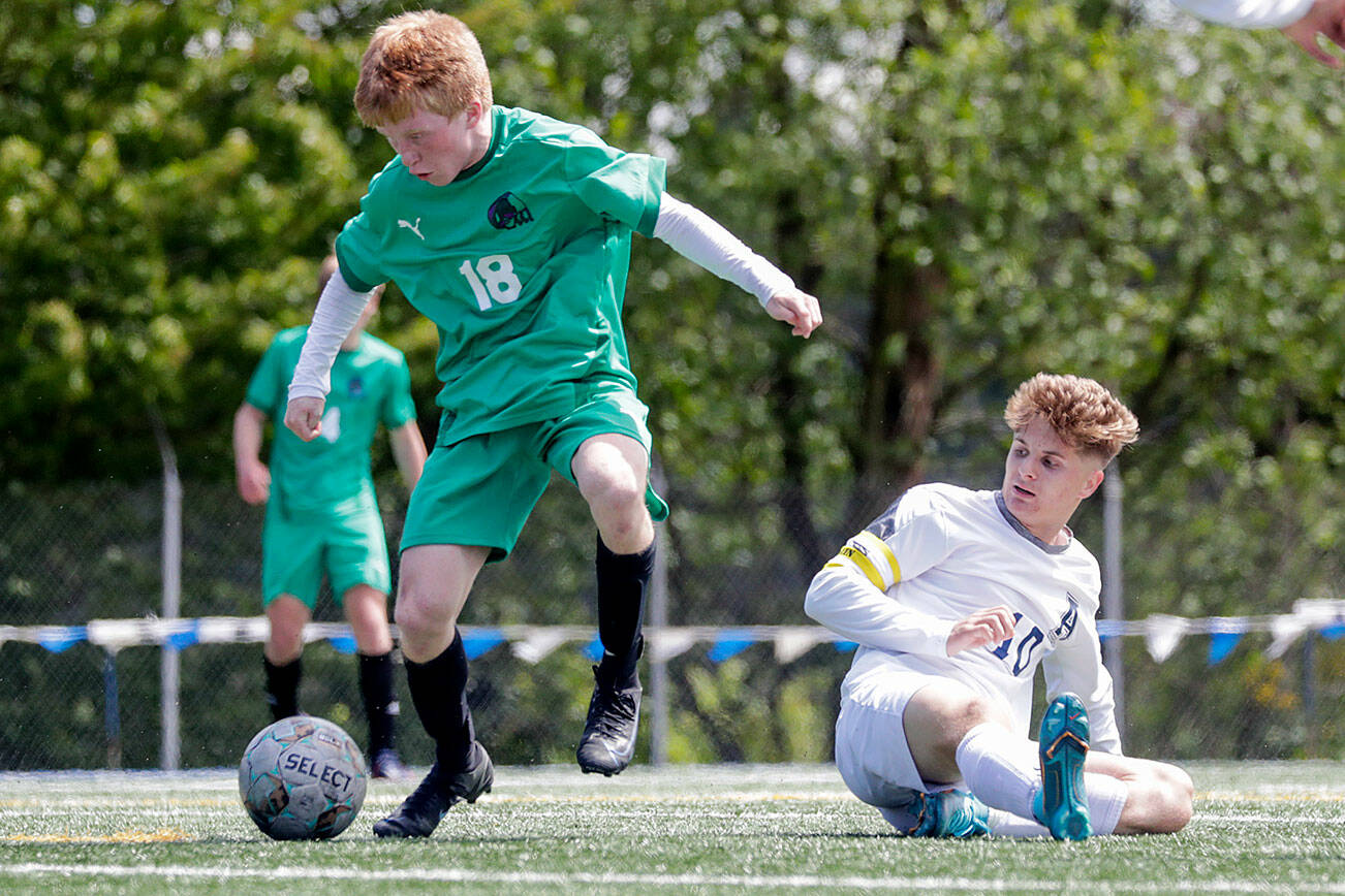 Edmonds-Woodway's Benjamin Hanson avoids a tackle by Arlington's Kayden Allen to score a goal in the second half Saturday afternoon at Shoreline Stadium in Shoreline, Washington on May 14, 2022.  The Warriors won 4-2. (Kevin Clark / The Herald)