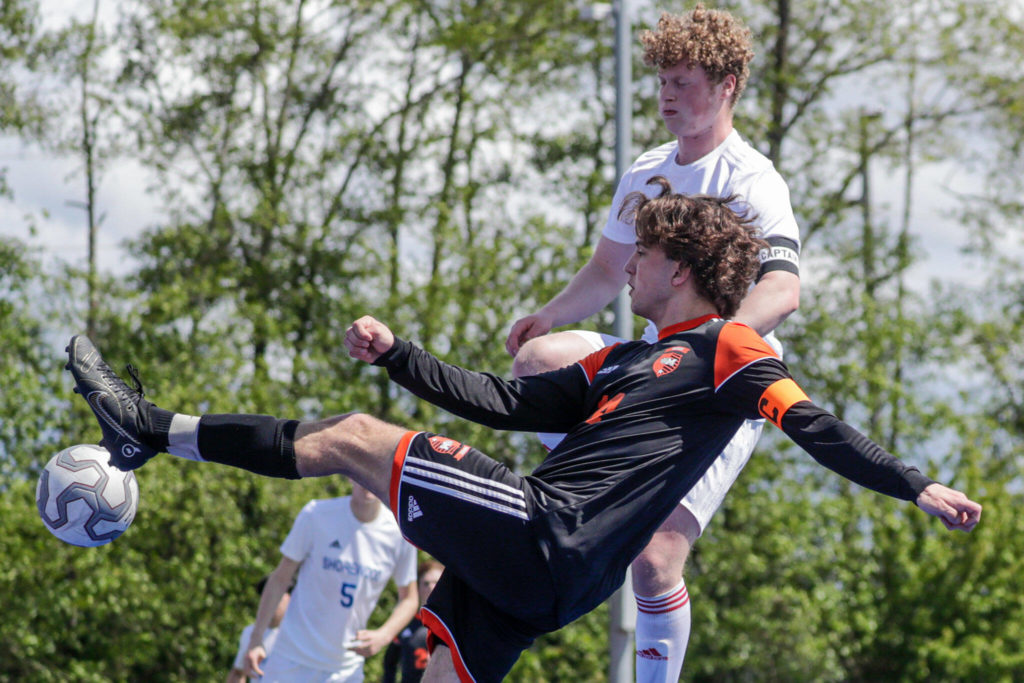 Monroe’s Caden Kaasa take a shot at goal with Shorewood’s Alex Panteleeff on Saturday afternoon at Shoreline Stadium in Shoreline, Washington on May 14, 2022. The Bearcats won 2-0. (Kevin Clark / The Herald)
