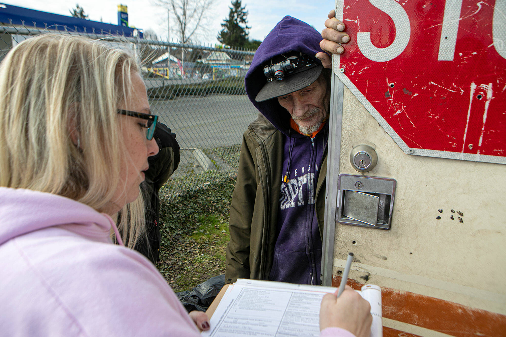 Community service counselor Mandy Jeffcott talks with Fred Prain while conducting a point-in-time count of people experiencing homelessness Feb. 22 in Everett. Prain, 61, had been living out of his RV. (Ryan Berry / The Herald)