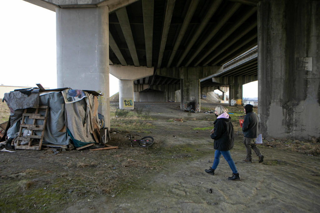 Mandy Jeffcott and Aaron King explore the area beneath a highway underpass while conducting a point-in-time count Feb. 22 in Everett. (Ryan Berry / The Herald)
