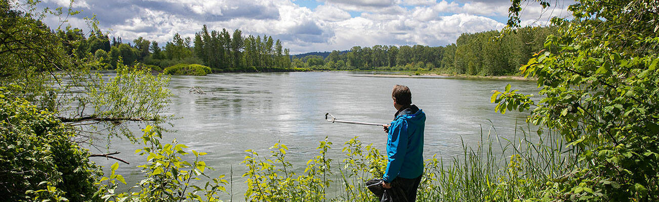 Doug Ewing looks out over a small section of the Snohomish River that he has been keeping clean for the last ten years on Thursday, May 19, 2022, at the Oscar Hoover Water Access Site in Snohomish, Washington. Ewing scours the shorelines and dives into the depths of the river in search of trash left by visitors, and has removed 59 truckloads of litter from the quarter-mile stretch over the past decade. (Ryan Berry / The Herald)