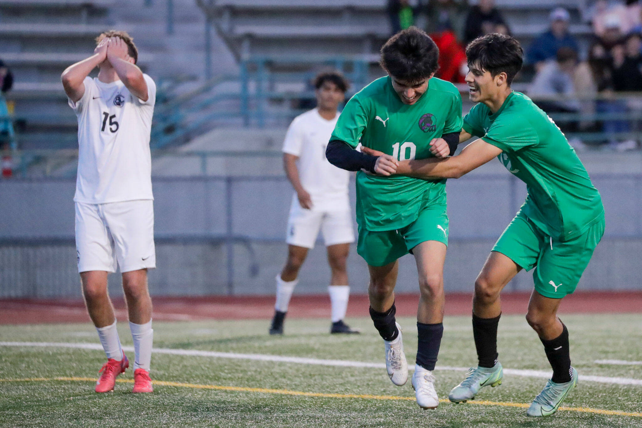 Bonney Lake’s James O’Callaghan stands dejected as Edmonds-Woodway’s Victor Ibarra (far right) celebrates Edgar Cabrera’s goal in the second half Tuesday at Edmonds-Woodway High School. The Warriors won 3-1. (Kevin Clark / The Herald)