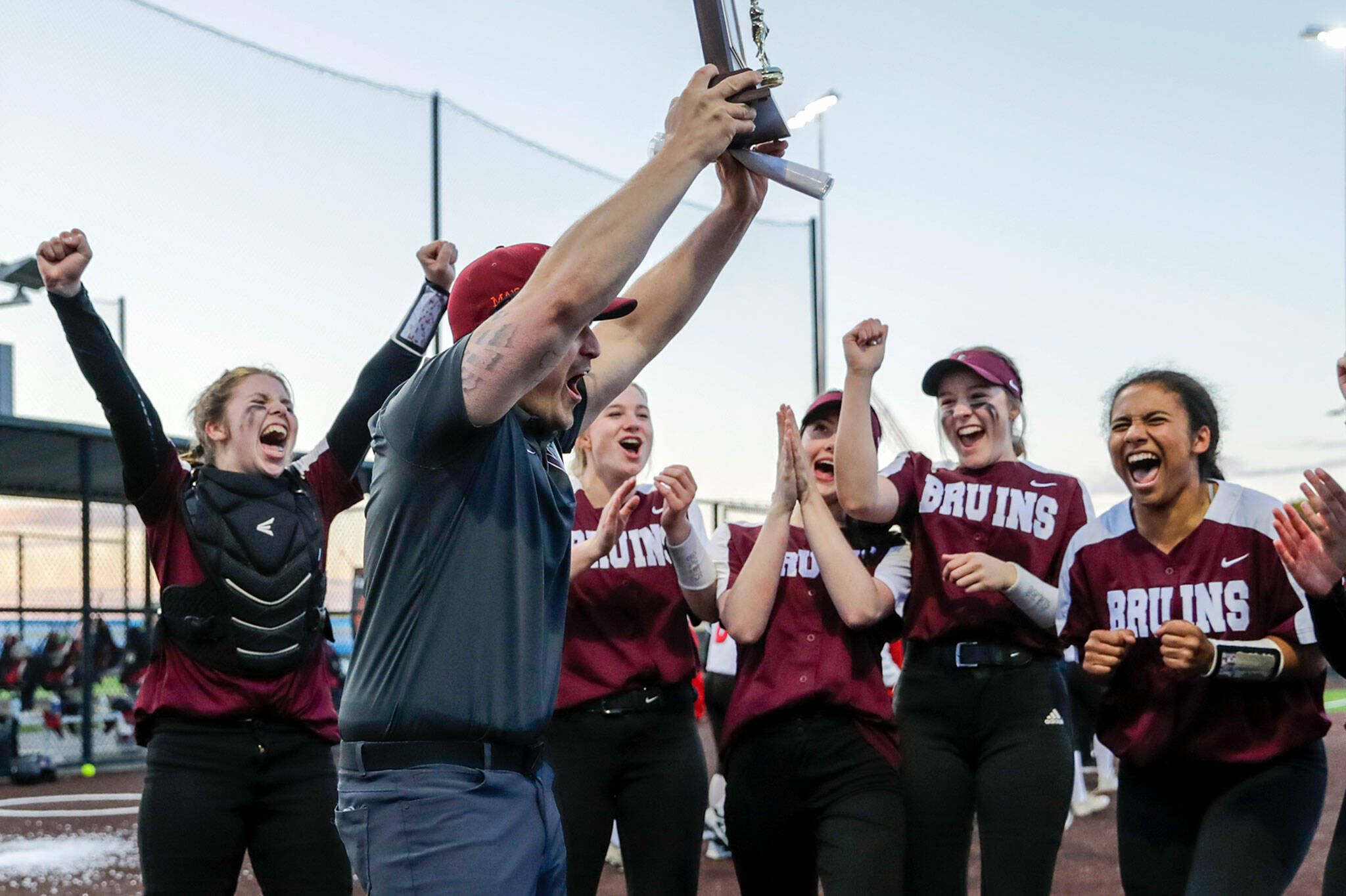 Cascade coach Mike Perrine raises the district championship trophy after the Bruins beat Snohomish 14-7 in the Class 3A District 1 Tournament title game Thursday evening at Phil Johnson Ballfields. (Kevin Clark / The Herald)