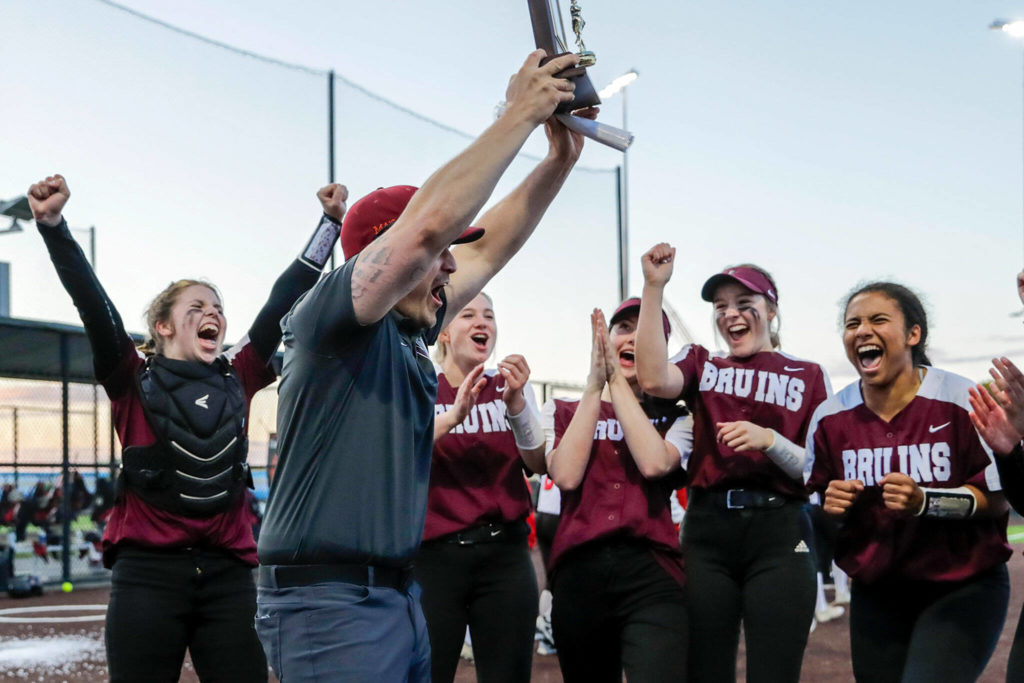 Cascade coach Mike Perrine raises the district championship trophy after the Bruins beat Snohomish 14-7 in the Class 3A District 1 Tournament title game Thursday evening at Phil Johnson Ballfields. (Kevin Clark / The Herald)
