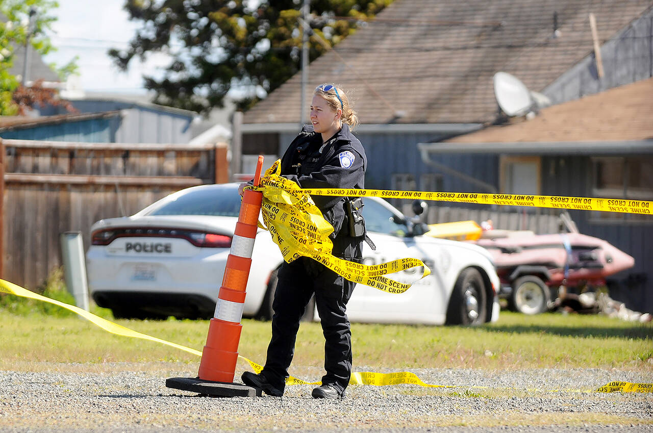 A Port Angeles police officer cordons off an empty lot at West Washington Street and Third Avenue in Sequim on Thursday morning as law enforcement officials investigate an incident in the area. (Michael Dashiell/Olympic Peninsula News Group)
