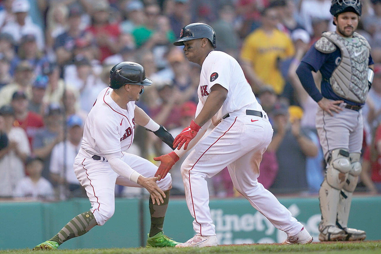 Boston Red Sox third baseman Rafael Devers, centert, celebrates his fifth inning home run with Enrique Hernandez during a baseball game against the Seattle Mariners, Saturday, May 21, 2022, in Boston. (AP Photo/Robert F. Bukaty)