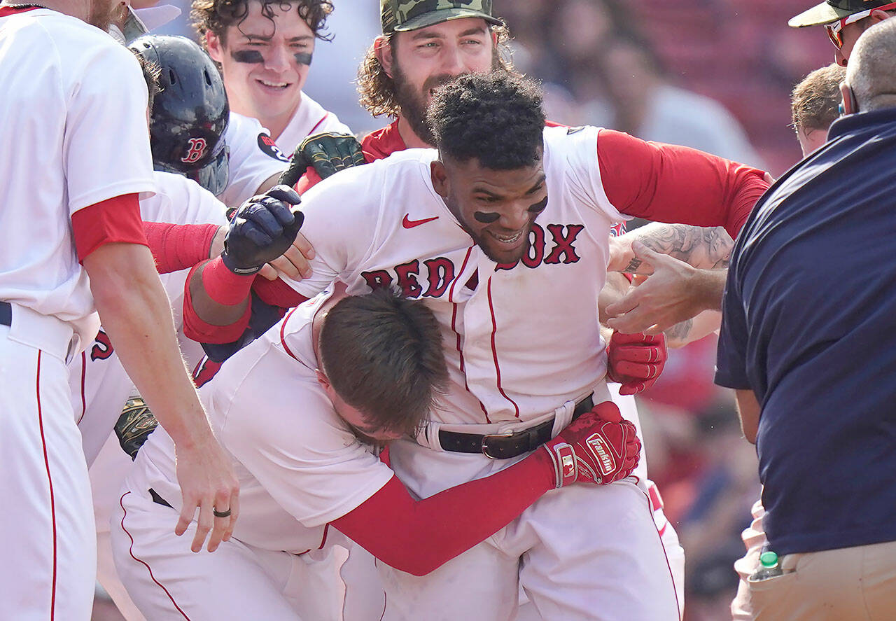 Boston Red Sox’s Franchy Cordero, center, celebrates with teammates after hitting a grand slam in the tenth inning of a game against the Seattle Mariners on Sunday in Boston. The Red Sox won 8-4. (AP Photo/Steven Senne)