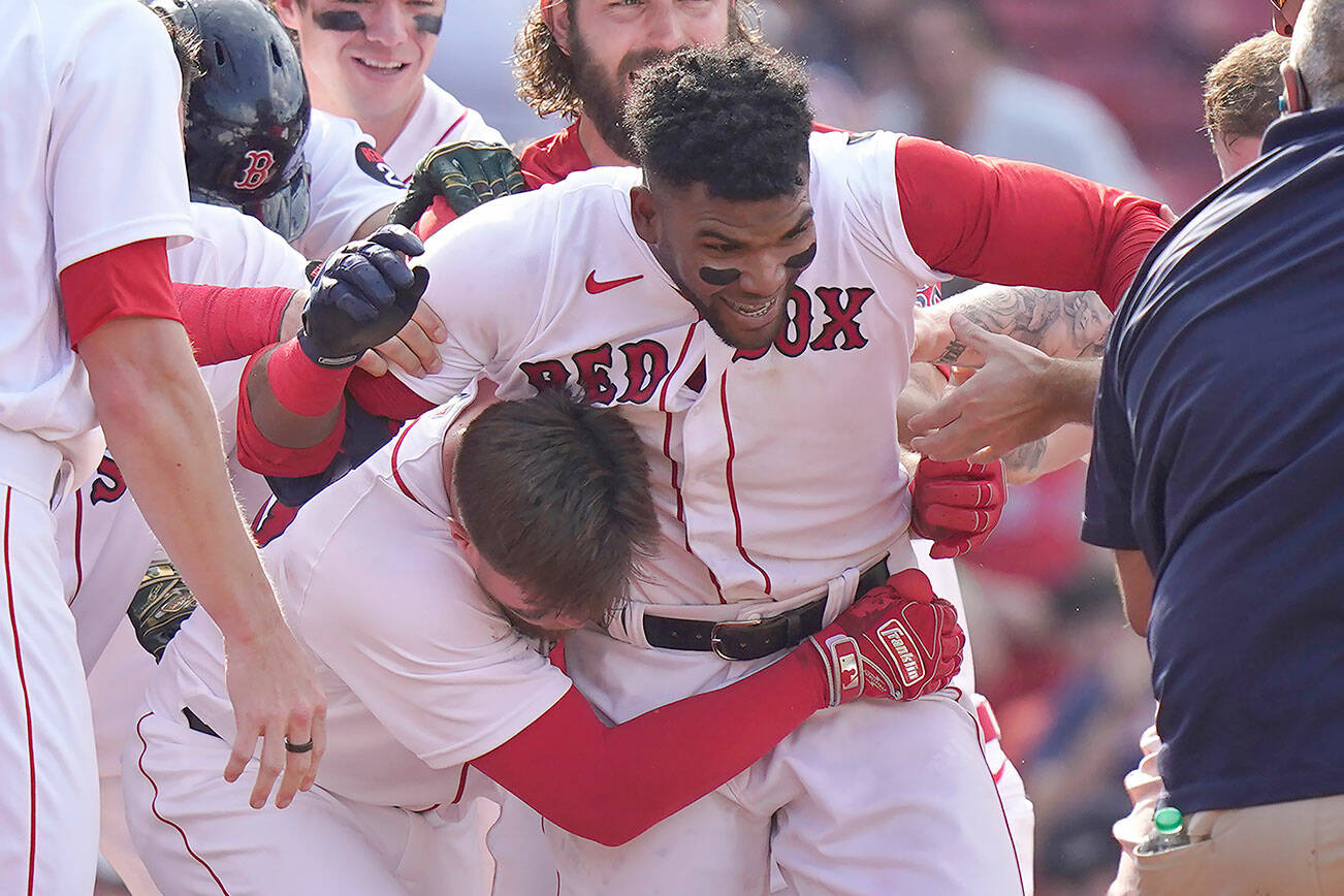 Boston Red Sox's Franchy Cordero, center, celebrates with teammates after hitting a grand slam in the tenth inning of a baseball game against the Seattle Mariners, Sunday, May 22, 2022, in Boston. The Red Sox won 8-4. (AP Photo/Steven Senne)