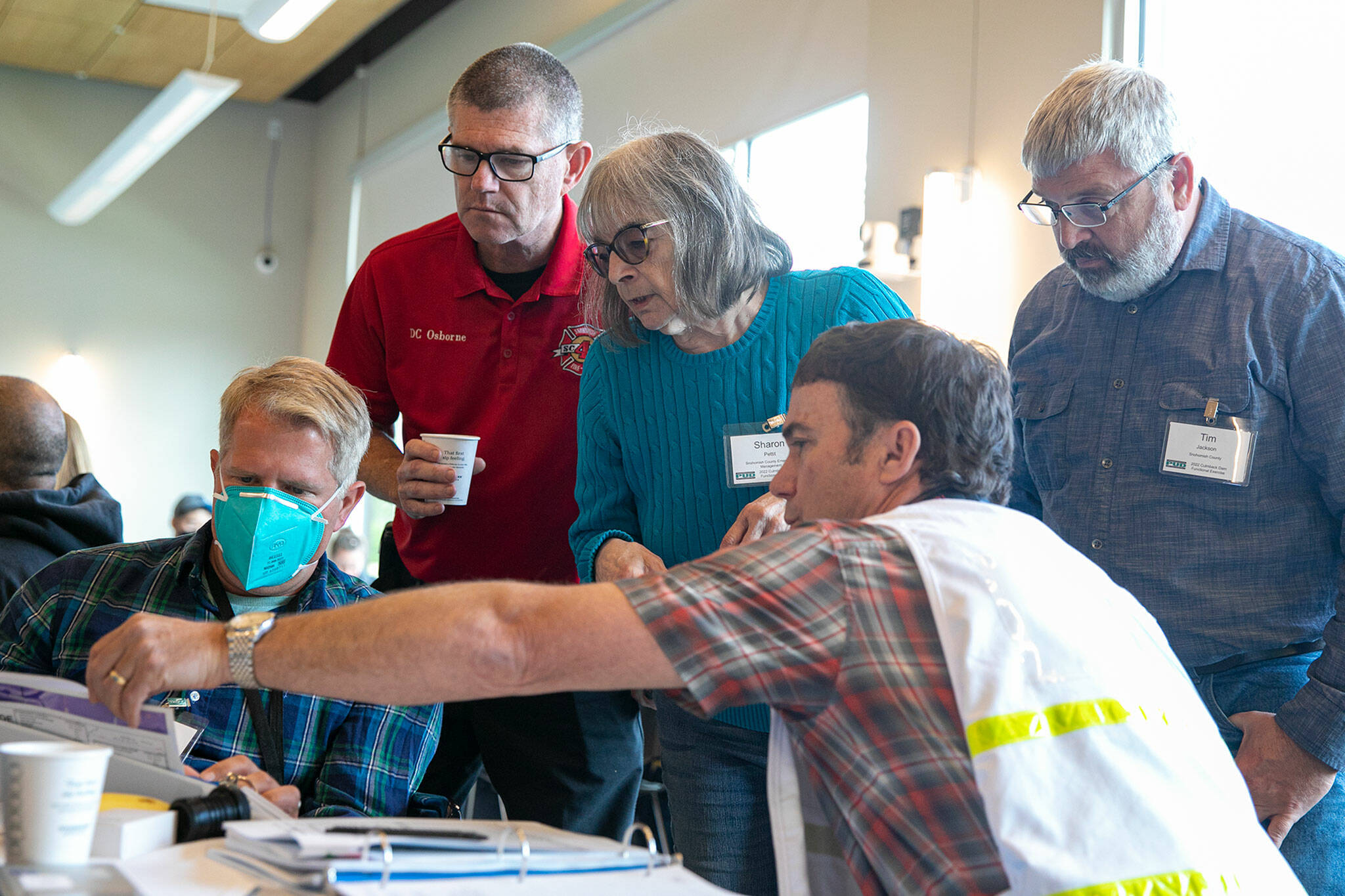 Snohomish PUD Principal Engineer Eric Schneider (front) points to a flood map while talking with (from left) the PUD’s Scott Spahr, Fire District 4 Deputy Chief Greg Osborne, Snohomish Building and Fire Official Sharon Pettit and Snohomish Public Works Utilities Manager Tim Jackson during a disaster simulation Wednesday in Sultan. (Ryan Berry / The Herald)