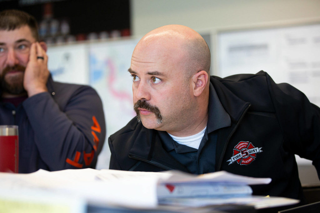 New Sultan Fire Chief Seth Johnson leans in to listen to fellow emergency workers during a disaster simulation Wednesday at Snohomish County Fire District 5 Station 51 in Sultan. (Ryan Berry / The Herald)
