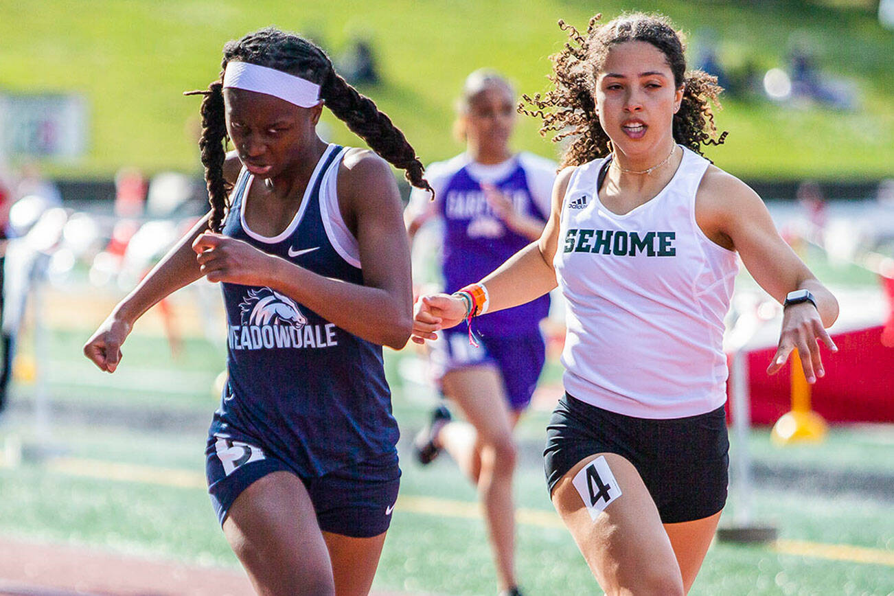 Meadowdale’s Tresley Love grimaces as she leans across the finish line for a photo finish with Sehome’s Jayda Darroch during Eason Invitational track and field meet on Saturday, April 23, 2022 in Snohomish, Washington. (Olivia Vanni / The Herald)