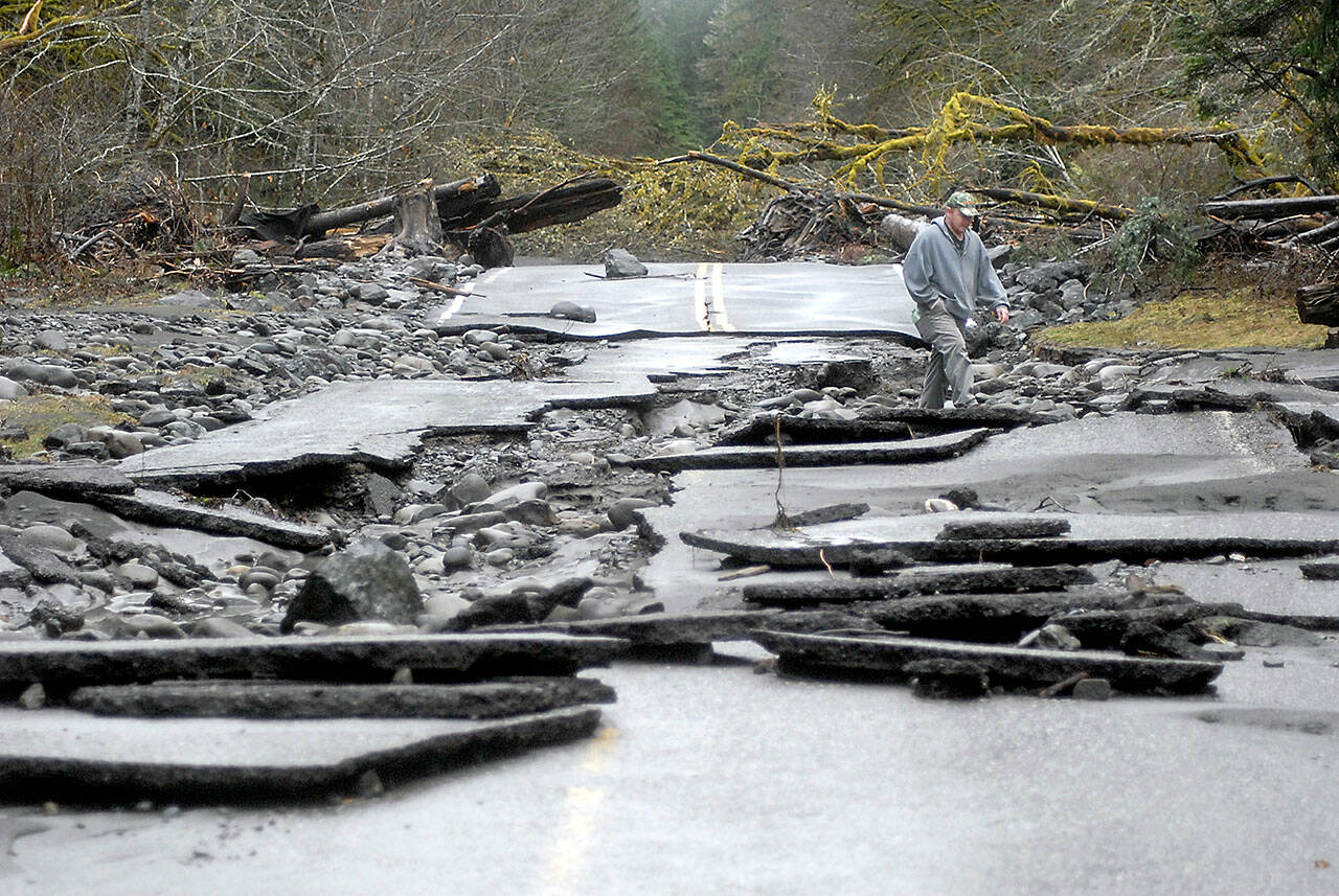 A man picks his way through the rubble of Olympic Hot Springs Road at the site of a washout in the Elwha River Valley of Olympic National Park in 2017. (Keith Thorpe / Peninsula Daily News file)