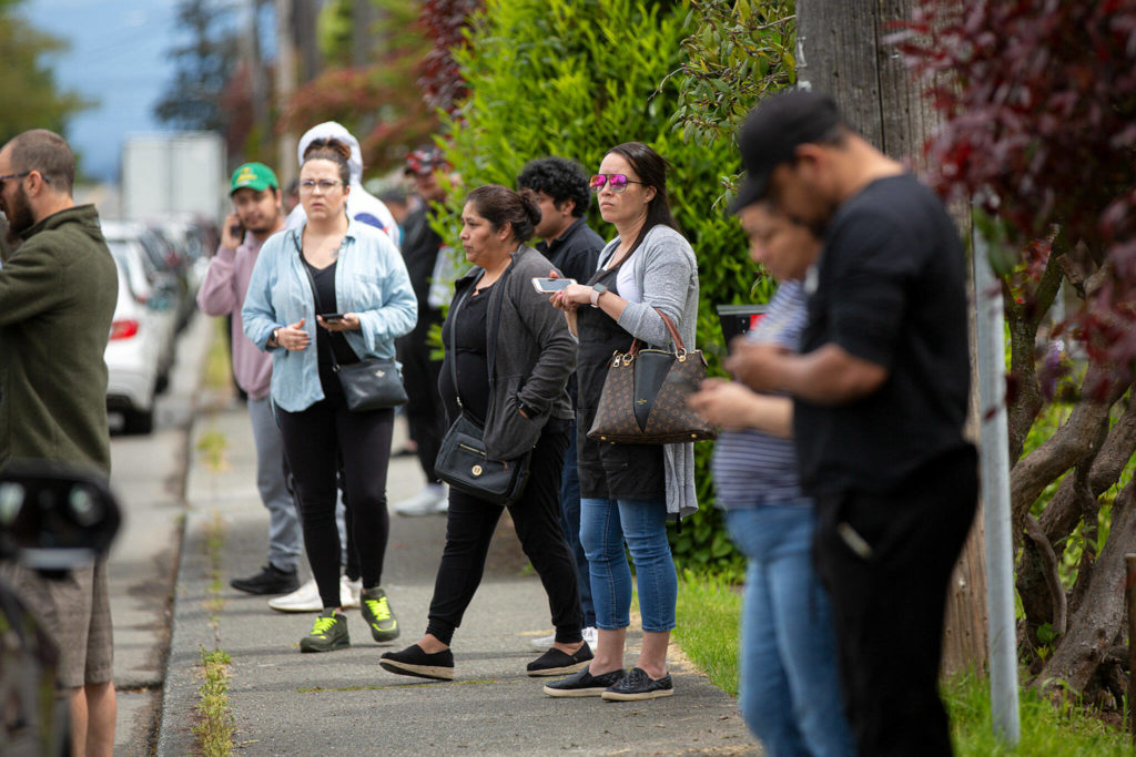 Family members gather across the street from Cascade High School as they await an explanation for a large police presence on the school’s campus Friday in Everett. (Ryan Berry / The Herald) 
