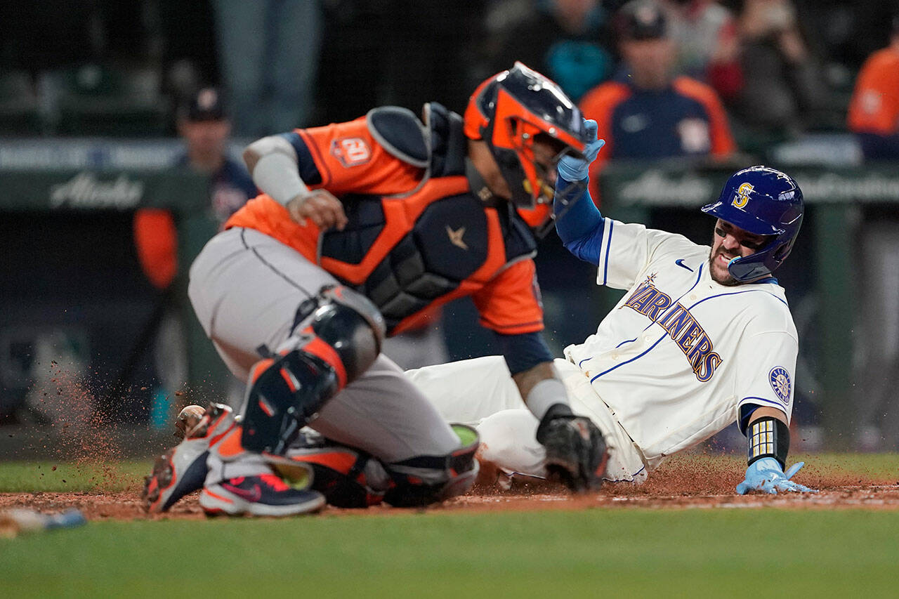 Seattle Mariners’ Luis Torrens, right, slides safely home past Houston Astros catcher Martin Maldonado to score on a RBI single hit by Ty France during the sixth inning of a game Sunday in Seattle. (AP Photo/Ted S. Warren)