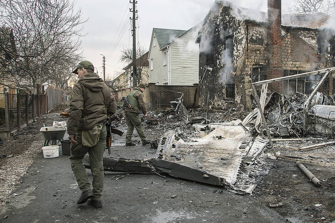 FILE - Ukrainian servicemen walk by fragments of a downed aircraft,  in in Kyiv, Ukraine, Friday, Feb. 25, 2022. The International Criminal Court's prosecutor has put combatants and their commanders on notice that he is monitoring Russia's invasion of Ukraine and has jurisdiction to prosecute war crimes and crimes against humanity. But, at the same time, Prosecutor Karim Khan acknowledges that he cannot investigate the crime of aggression. (AP Photo/Oleksandr Ratushniak, File)