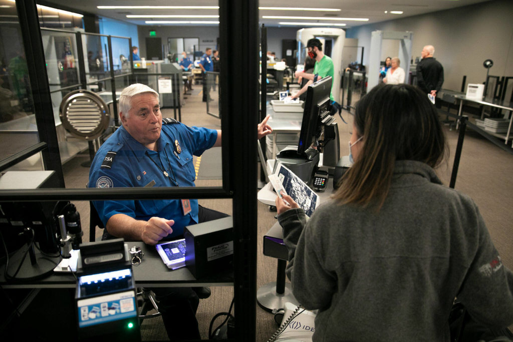 TSA officer Jerry Drews speaks with a person in the security line at Paine Field. (Ryan Berry / The Herald)
