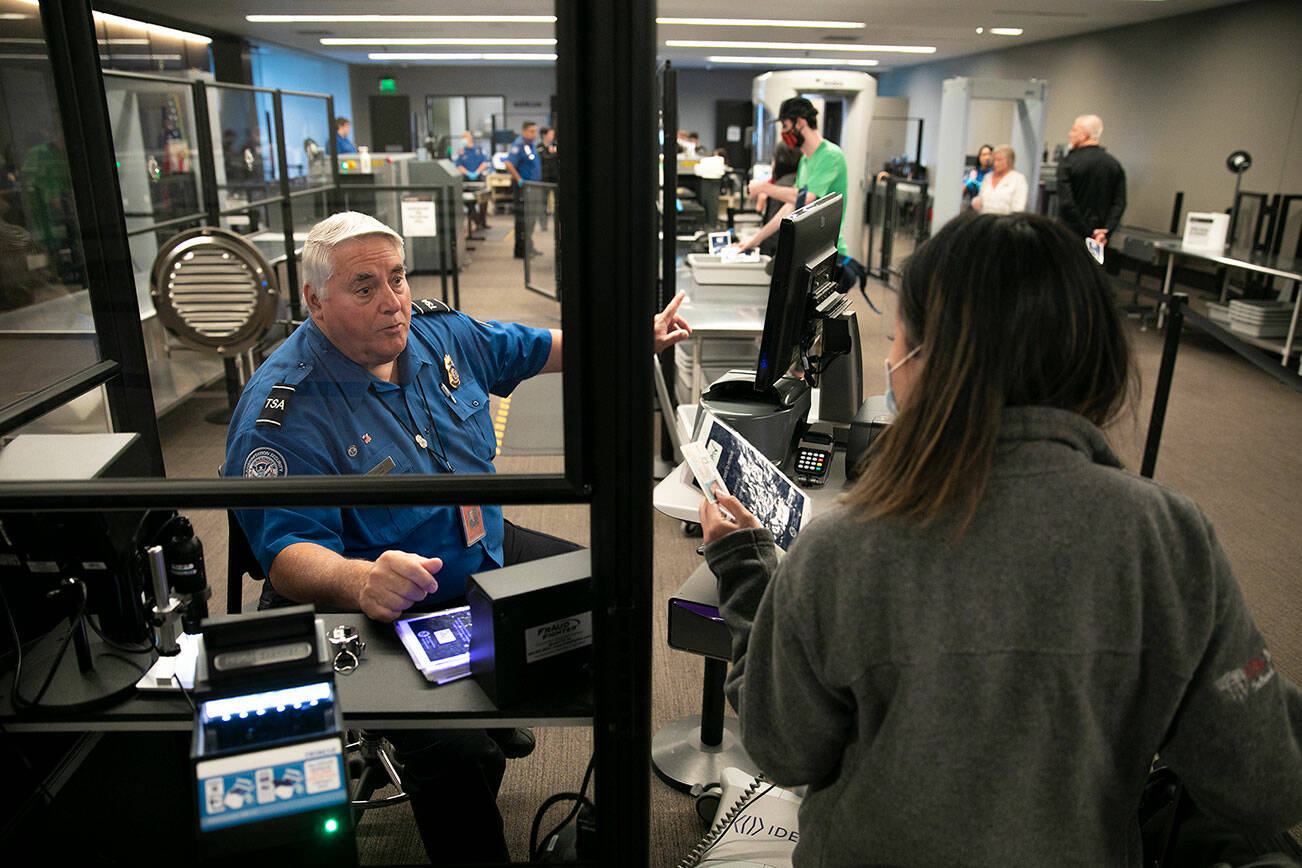 Transportation Security Officer Jerry Drews speaks with a person in the security line Friday, May 27, 2022, at Paine Field in Everett, Washington. (Ryan Berry / The Herald)