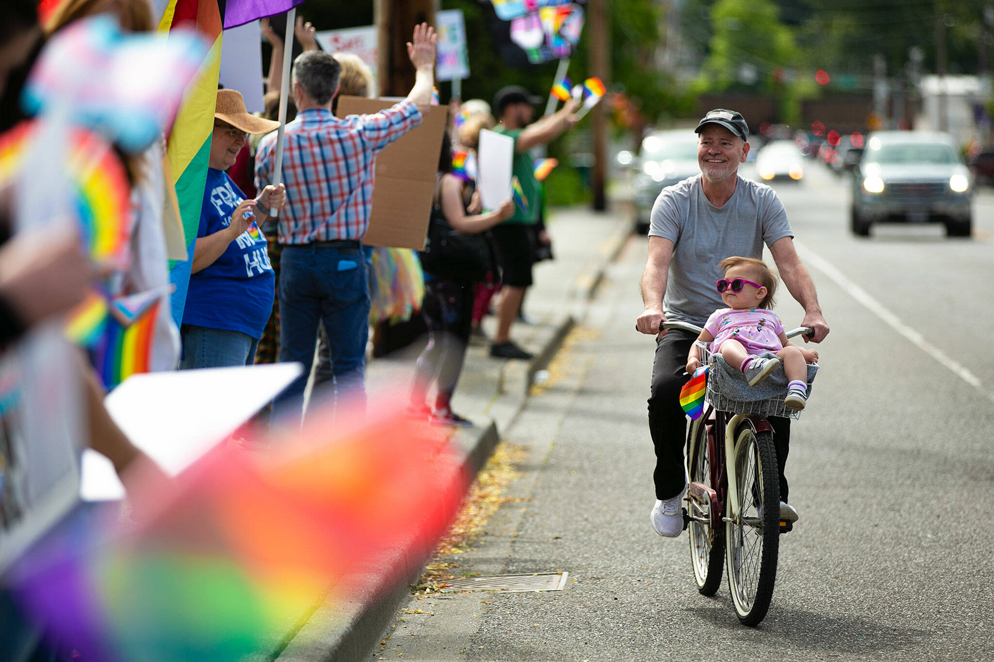 One-year-old Amiyah hitches a bicycle ride from her grandfather Bob as the two ride around during a rally in support of LGBTQ+ students on Monday in front of the Marysville School District Service Center in Marysville. (Ryan Berry / The Herald)