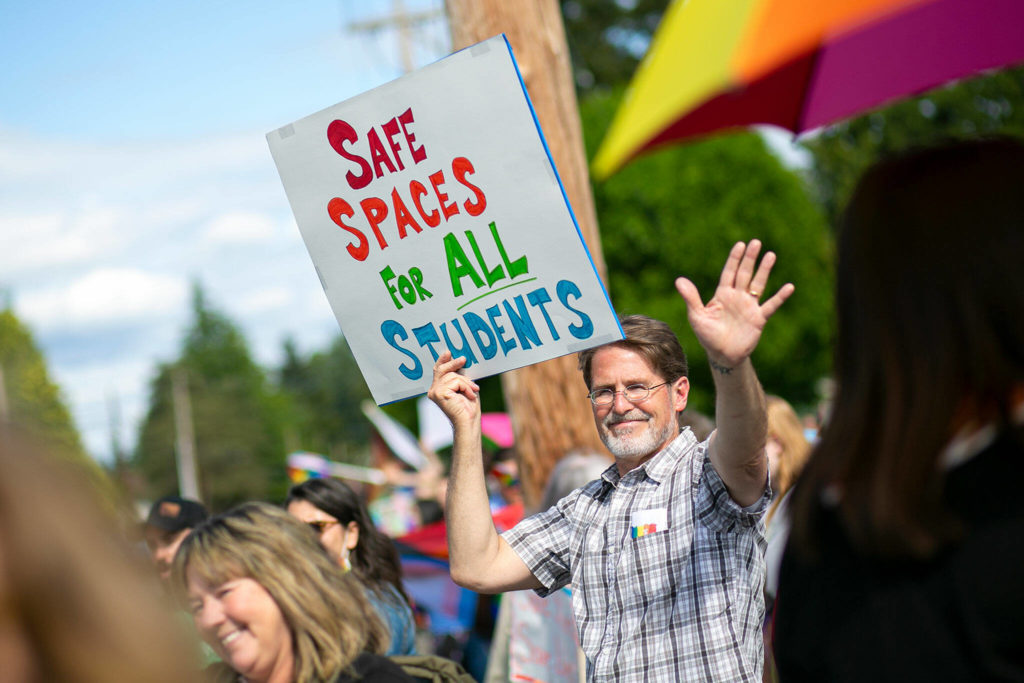 Jim Strickland, a teacher in Marysville Getchell’s 18-21 program who has been at the school for ten years, holds up a sign and waves at passing cars during a rally in support of LGBTQ+ students on Monday in front of the Marysville School District Service Center in Marysville. (Ryan Berry / The Herald)
