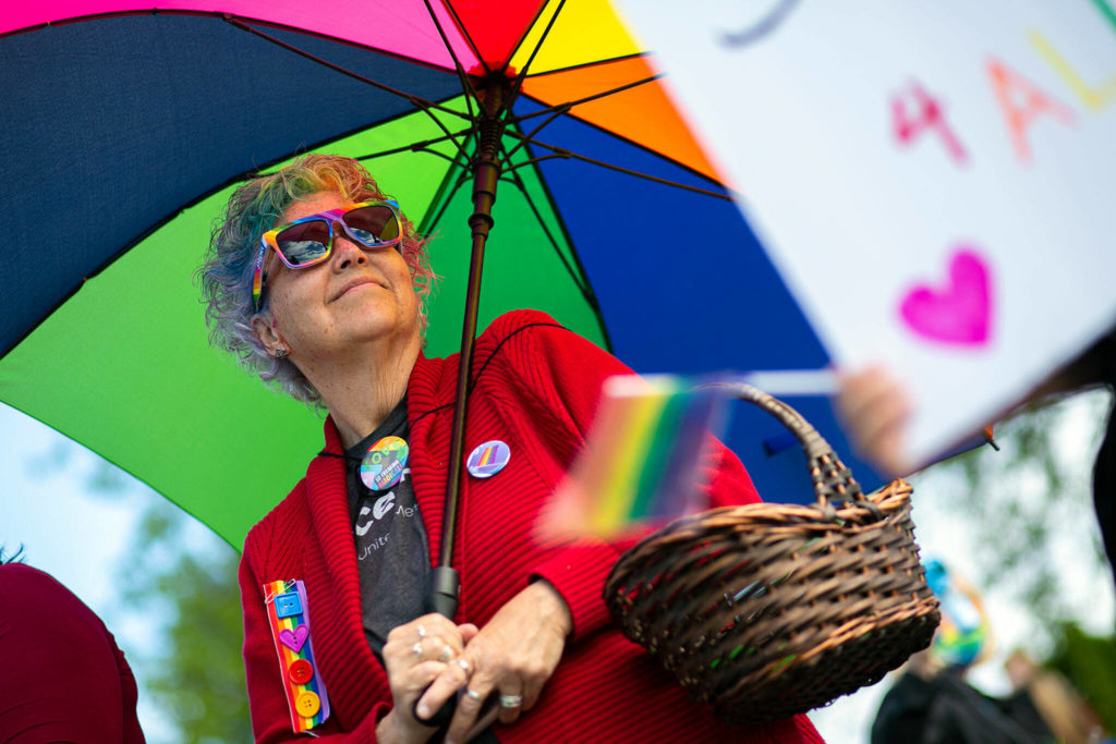 Nina Purcell stands under an umbrella and watches as cars pass by and honk in support during a rally backing LGBTQ+ students on Monday in front of the Marysville School District Service Center in Marysville. (Ryan Berry / The Herald)
