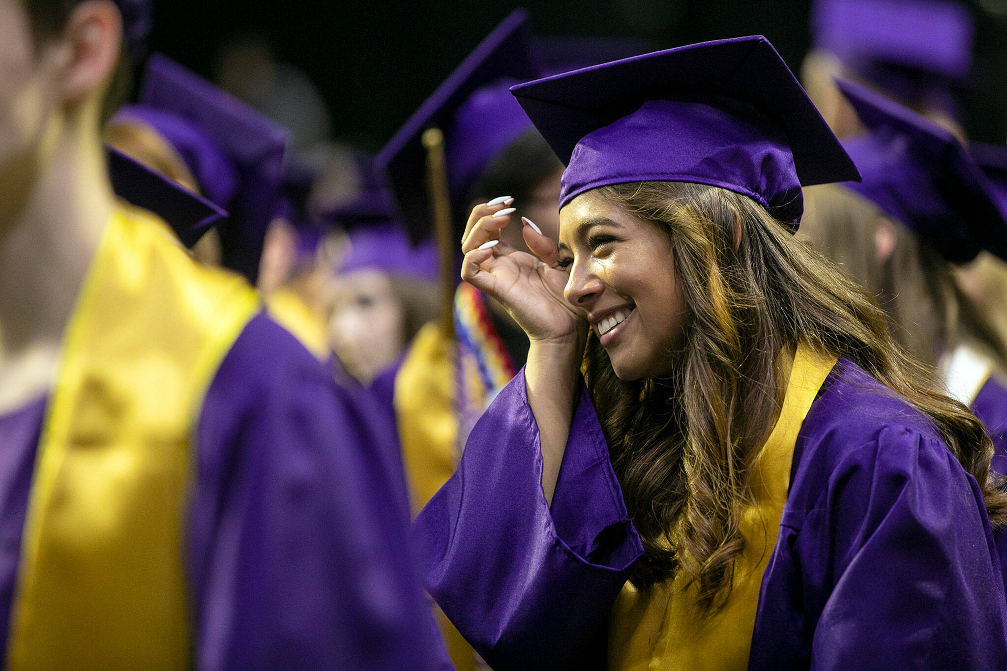 A student wipes away tears as the 592 graduates take their places during the processional at Lake Stevens High School’s 2022 commencement ceremony Tuesday at Angel of the Winds Arena in Everett. (Ryan Berry / The Herald)