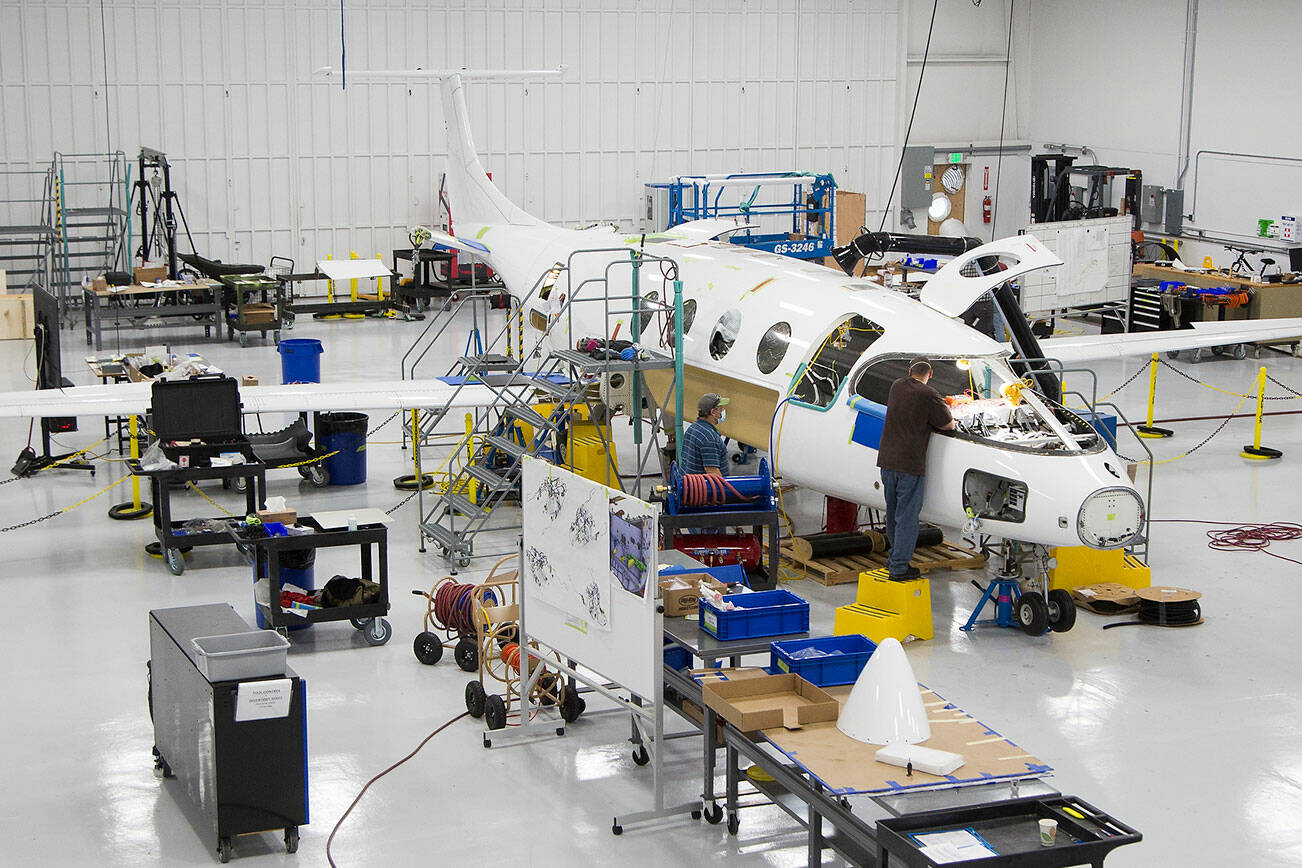 Workers build the first all electric plane, the Eviation Alice, on Wednesday, Sept. 8, 2021 in Arlington, Washington.  The plane is designed for regional travel and to carry nine passengers. (Andy Bronson / The Herald)