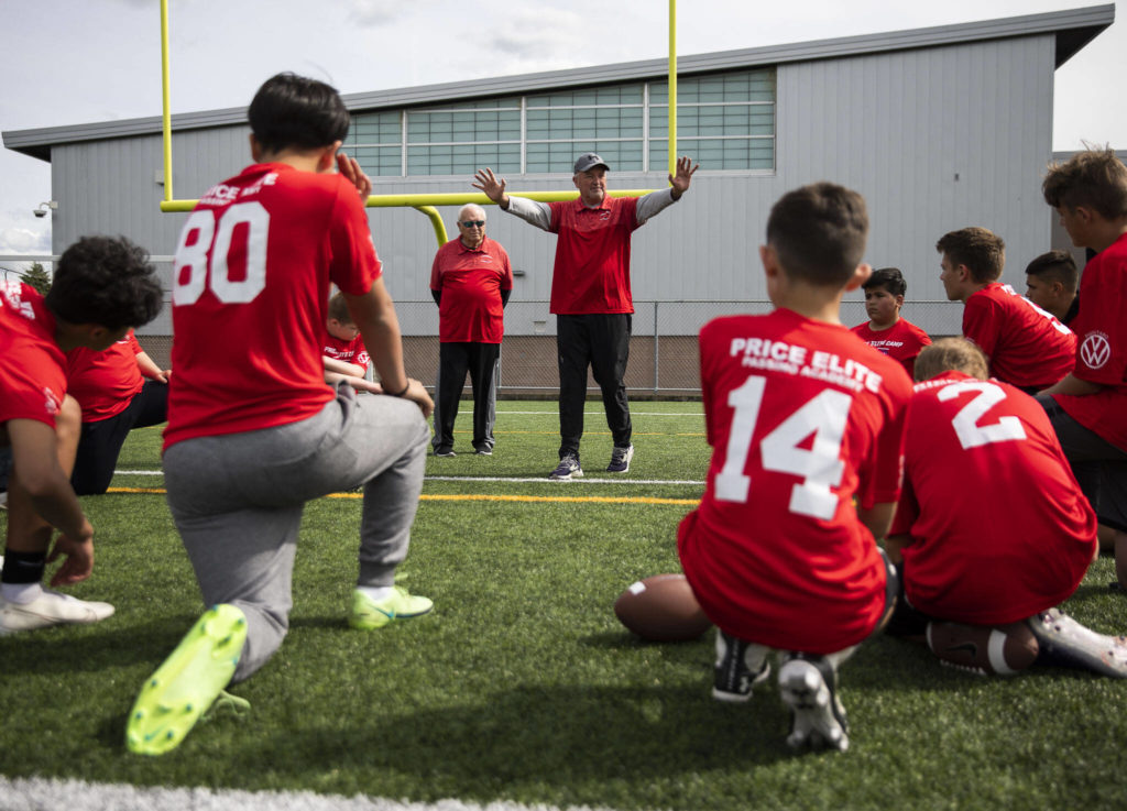 Mike Price (left) listens while his sonl, Eric, walks through a drill with the players the attending Price Elite Passing Academy on Wednesday at Bagshaw Field in Everett. (Olivia Vanni / The Herald)
