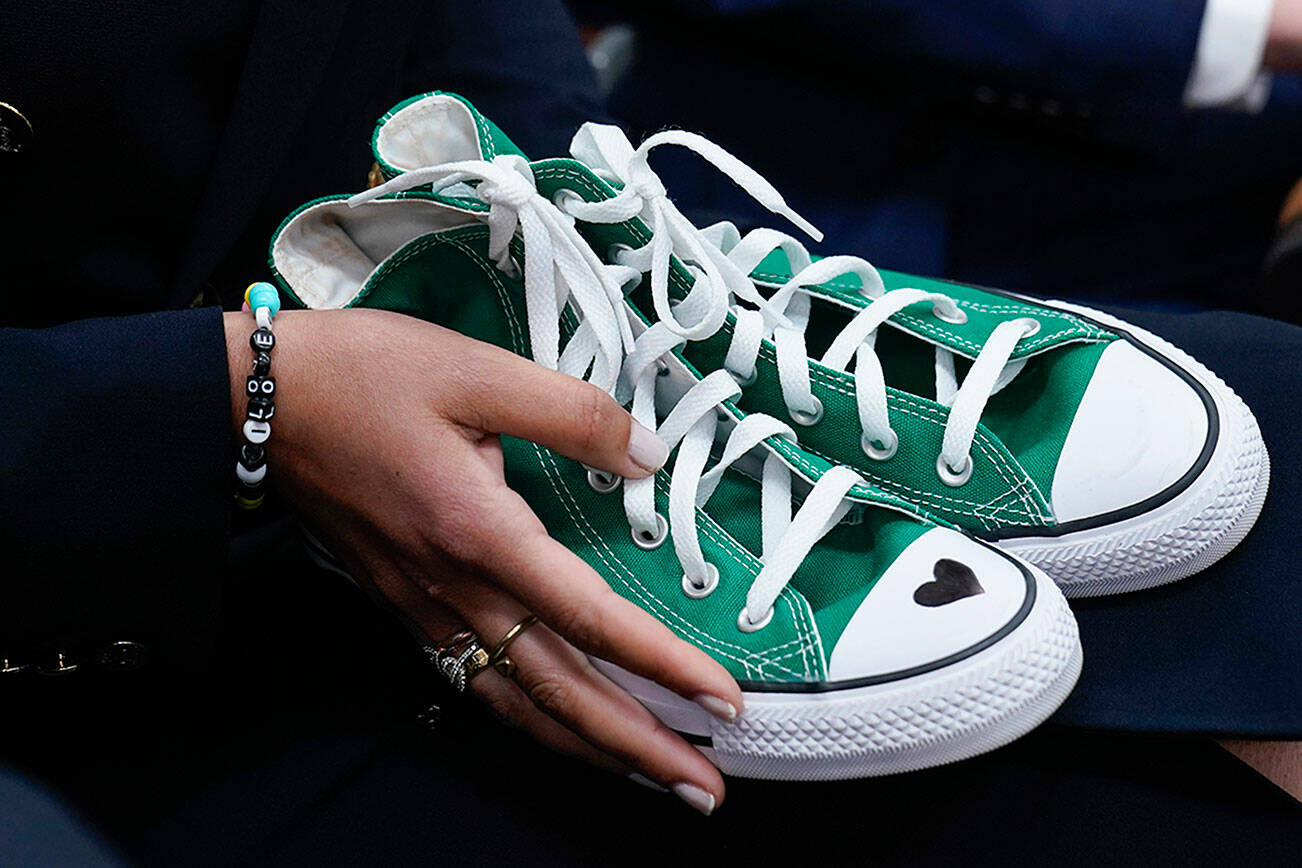 CORRECTS A MISSTATEMENT BY MATTHEW MCCONAUGHEY ABOUT THE ORIGIN OF THE SHOES - Camila Alves McConaughey holds a pair of green Converse tennis shoes similar to those worn by Uvalde shooting victim Maite Yuleana Rodriguez, 10, as her husband Matthew McConaughey, a native of Uvalde, Texas, joins White House press secretary Karine Jean-Pierre for the daily briefing at the White House in Washington, Tuesday, June 7, 2022. McConaughey said at the press briefing that his wife was holding a pair of sneakers worn by the girl. The shoes were similar, but they were not the girl’s sneakers. (AP Photo/Susan Walsh)