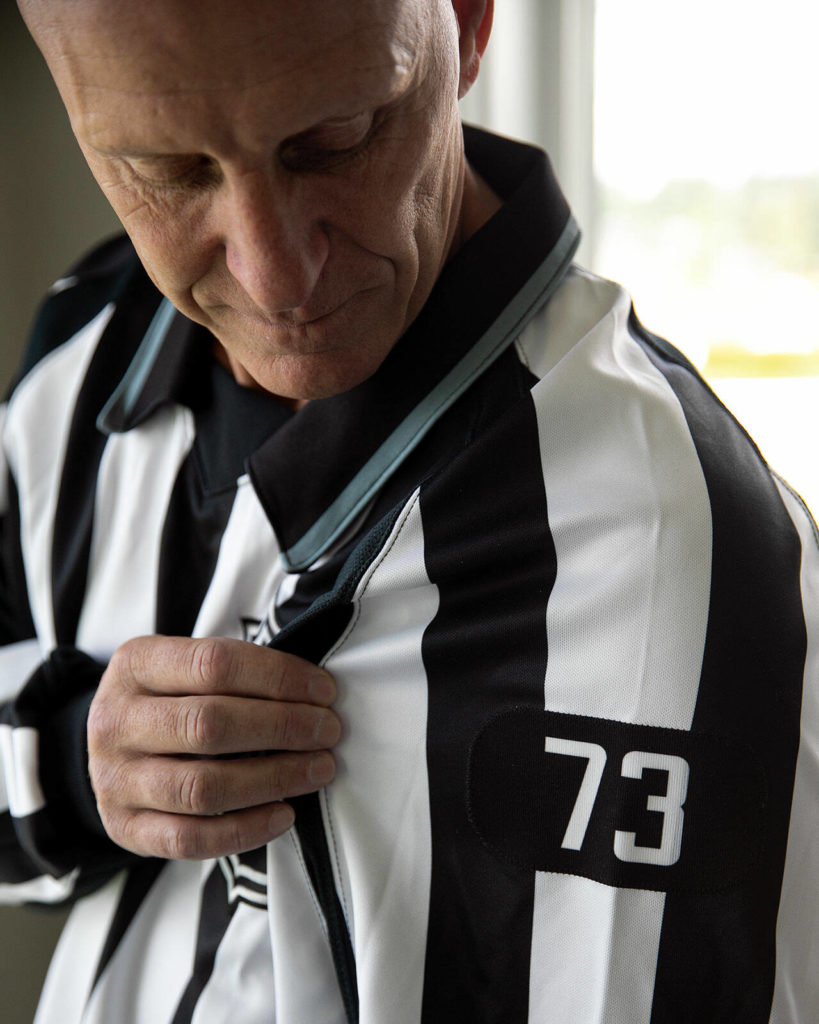 Vaughan Rody looks down at his number, 73, which he wore during his entire 22-year NHL career, on June 6 at his home in Lake Stevens. The league will keep his number vancant for the upcoming season before allowing new refs to wear it the following year. (Ryan Berry / The Herald)
