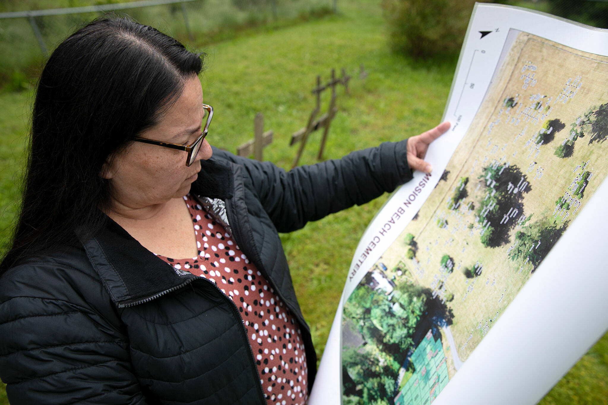 Candy Hill-Wells, funeral services officer for the Tulalip Tribes, looks over a map of burials while searching for specific graves at Mission Beach Cemetery on June 14 in Tulalip. (Ryan Berry / The Herald)