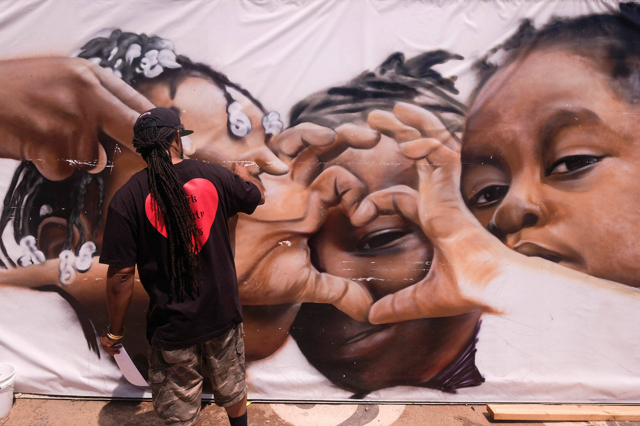 Artist Enkone works on a mural during a Juneteenth commemoration at Leimert Park Plaza on Saturday, June 19, 2021, in Los Angeles. (Ringo H.W. Chiu / Associated Press)