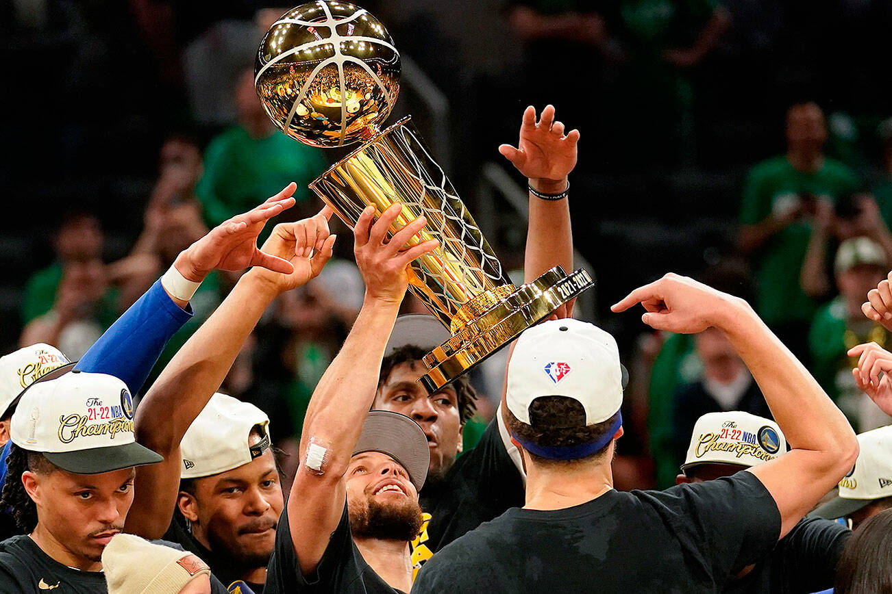 Golden State Warriors guard Stephen Curry, center, holds up the Larry O'Brien Championship Trophy with teammates after defeating the Boston Celtics in Game 6 of basketball's NBA Finals, Thursday, June 16, 2022, in Boston. (AP Photo/Steven Senne)