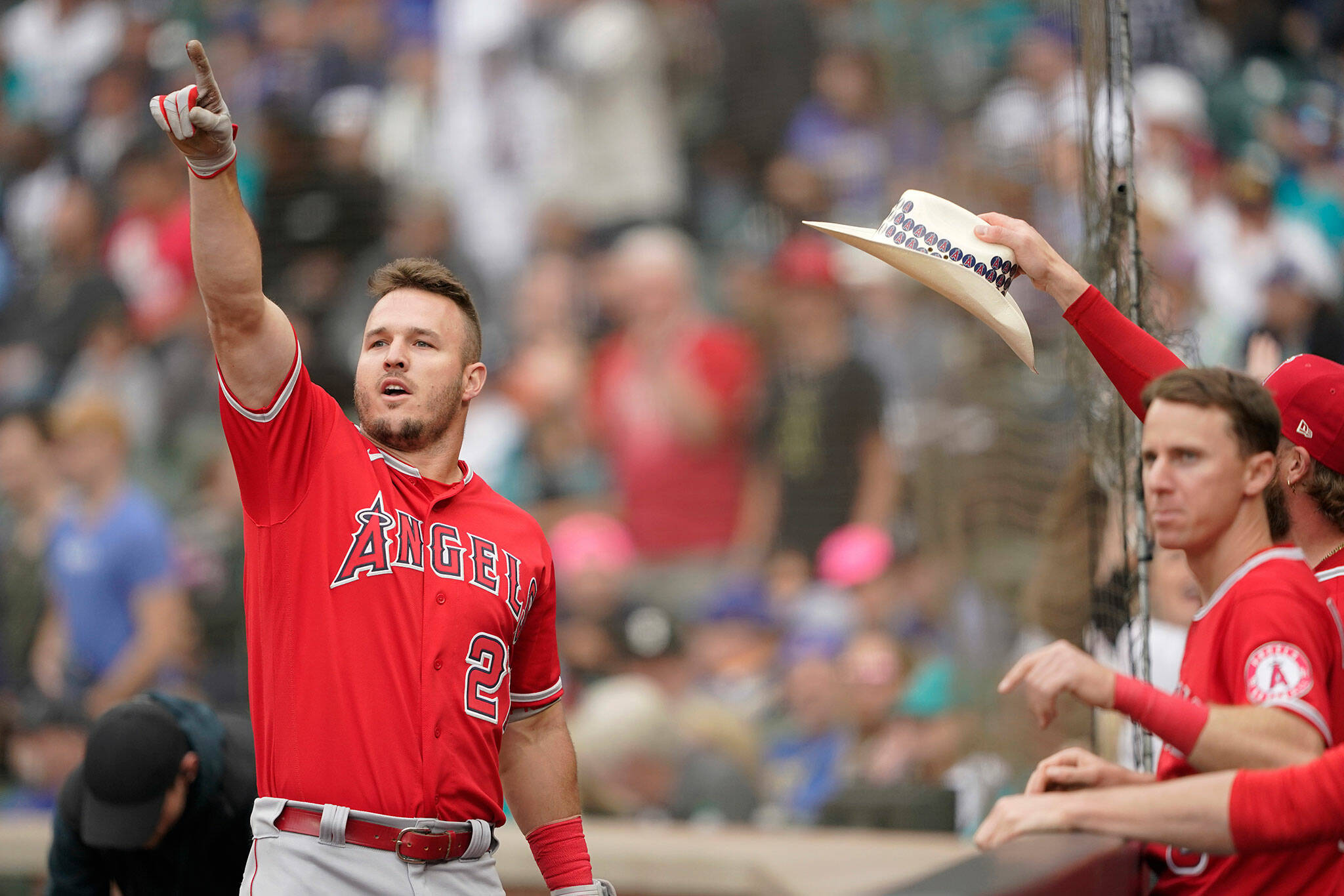 The Angels’ Mike Trout (left) points toward the outfield as he is greeted at the dugout after hitting a two-run home run in the tenth inning of the first baseball game of a doubleheader against the Mariners on Saturday in Seattle. (AP Photo/Ted S. Warren)