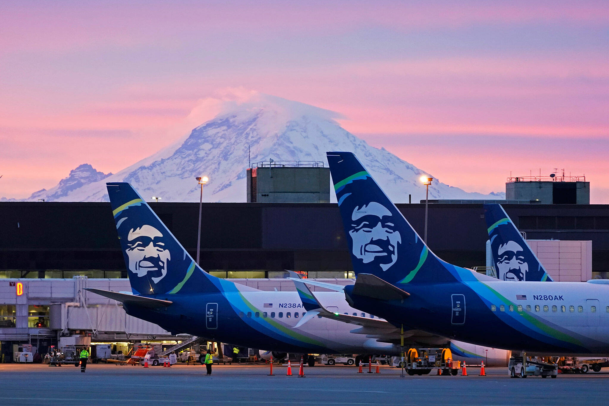 Alaska Airlines planes parked at gates with Mount Rainier in the background at sunrise, on March 1, 2021, at Seattle-Tacoma International Airport in Seattle. (AP Photo/Ted S. Warren, File)