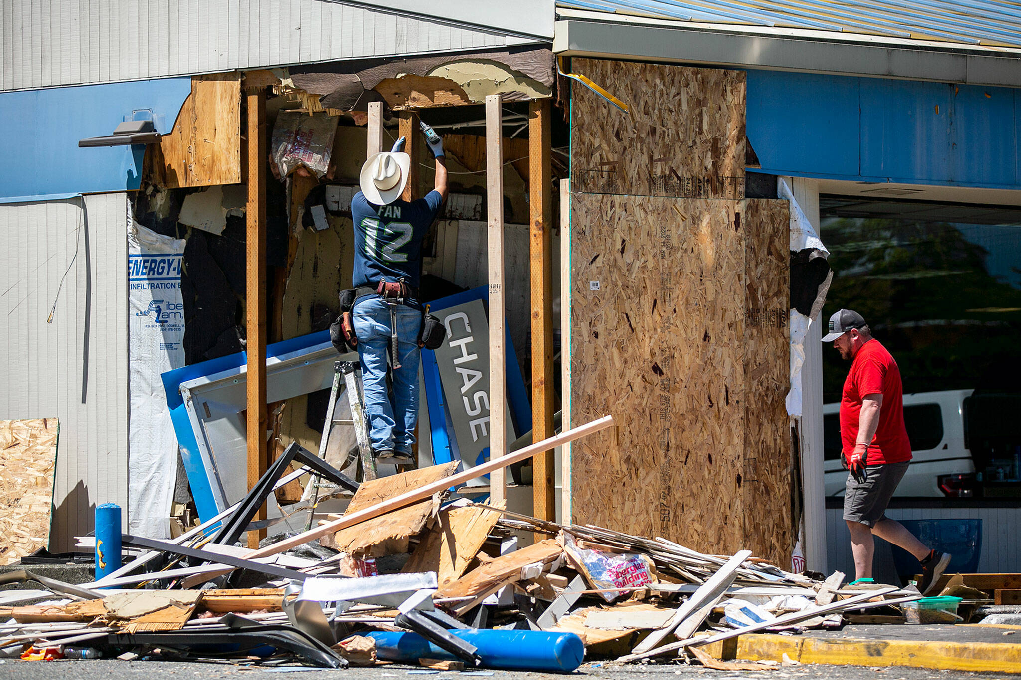 A worker reinforces the exterior wall of a Chase Bank that was partially destroyed the night before by a man driving a front-end loader on Thursday, June 23, 2022, on Alderwood Mall Boulevard in Lynnwood, Washington. (Ryan Berry / The Herald)