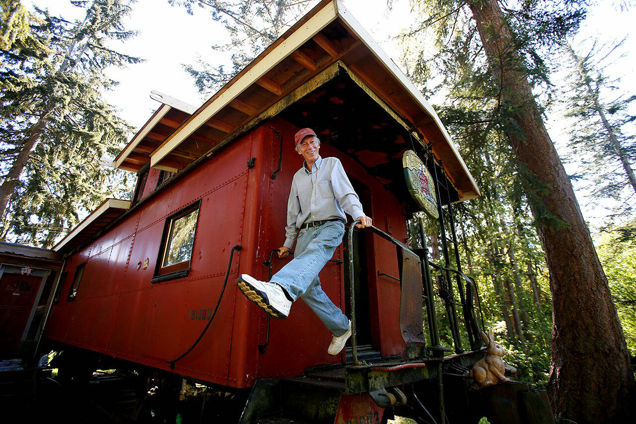 Pedaling his legs as he holds onto hand rails, Whidbey Island celebrity Jim Freeman shows off the railroad caboose he calls home in 2016 in Freeland. Freeman, 74, known as the Conductor of Fun, died June 19. (Andy Bronson / The Herald)