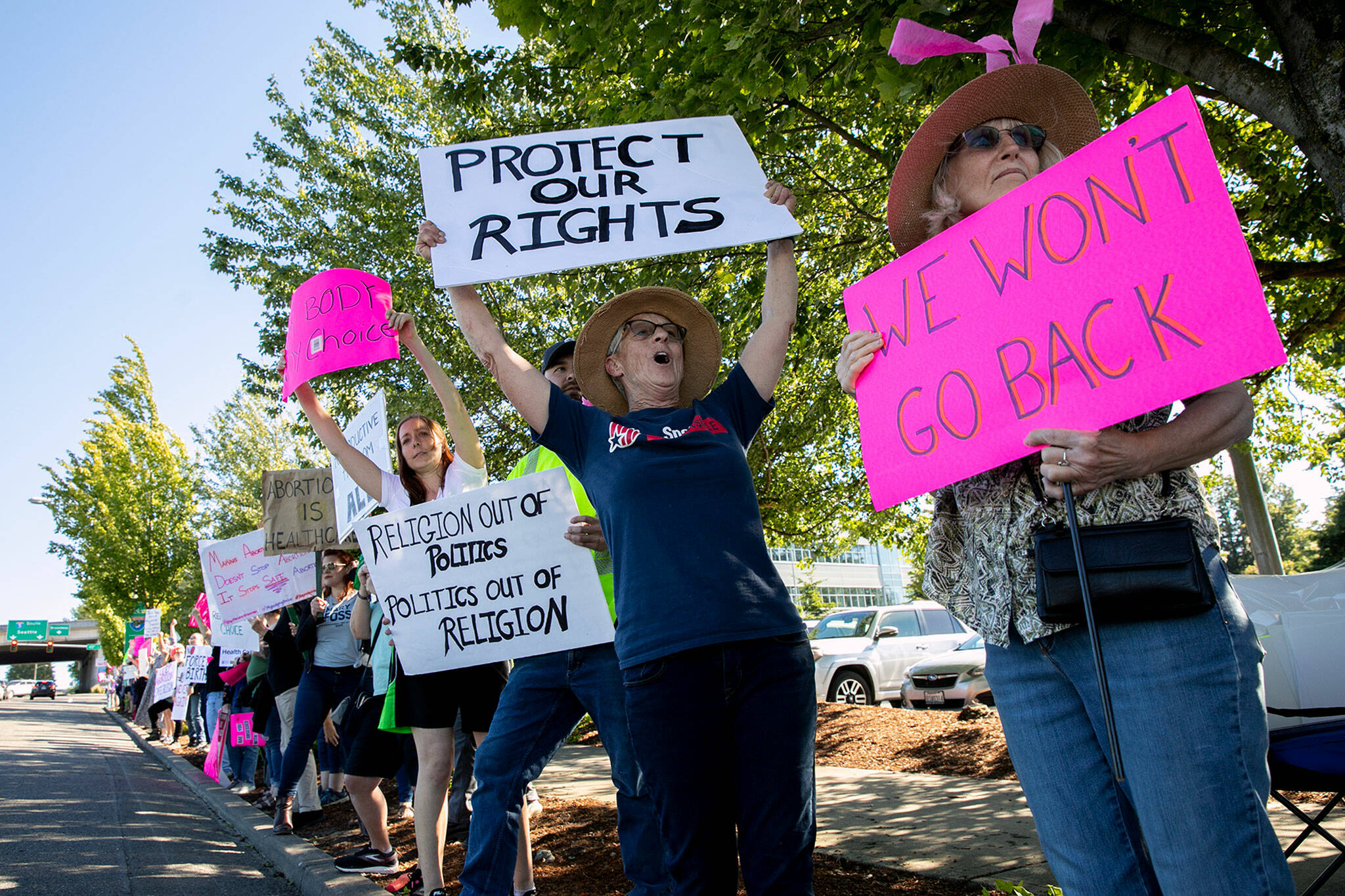 Sandra Oleson, center, holds up a “Protect Our Rights” sign and shouts for support from passing vehicles during a protest against the Supreme Court’s decision to overturn Roe v. Wade on Friday along Broadway in Everett, Washington. (Ryan Berry / The Herald)