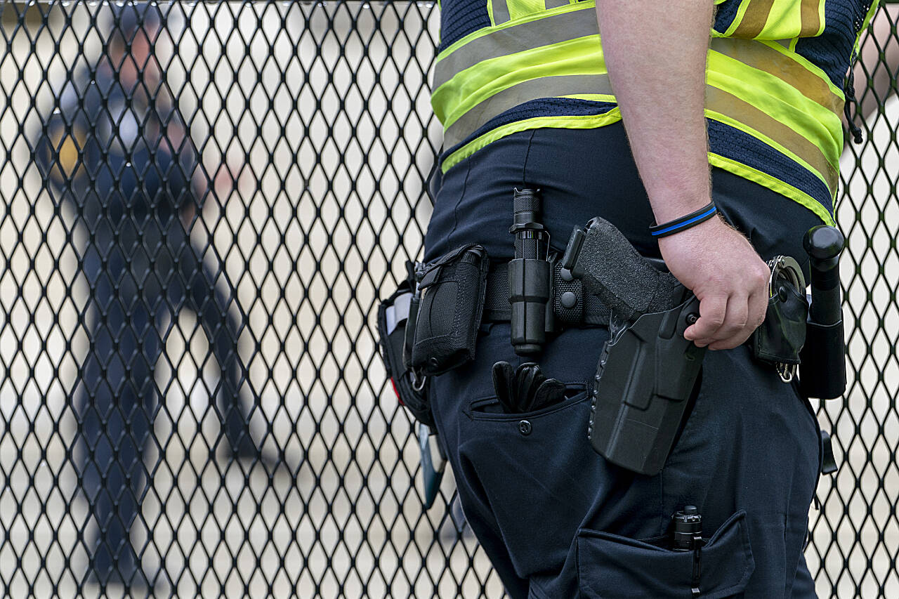 A Capitol Police officer rests his hand near his gun as he works by the anti-scaling fencing outside the Supreme Court, Thursday, June 23, 2022, in Washington. (Jacquelyn Martin / Associated Press)