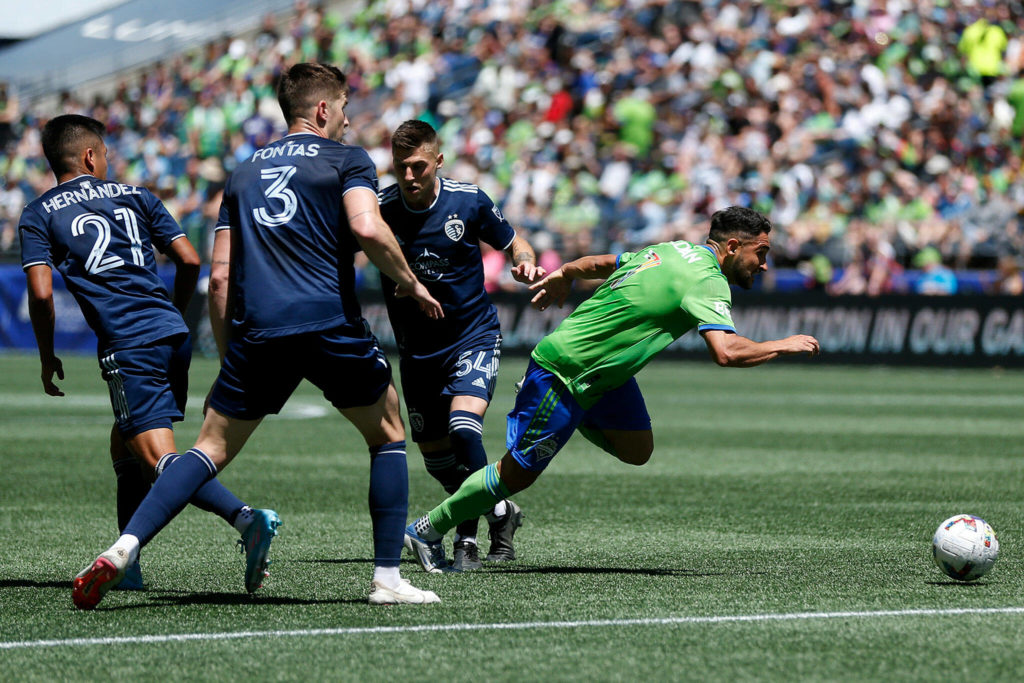 The Seattle Sounders’ Cristian Roldan sneaks through three defenders on his way to the net against Sporting KC on Saturday, June 25, 2022, at Lumen Field in Seattle, Washington. (Ryan Berry / The Herald)
