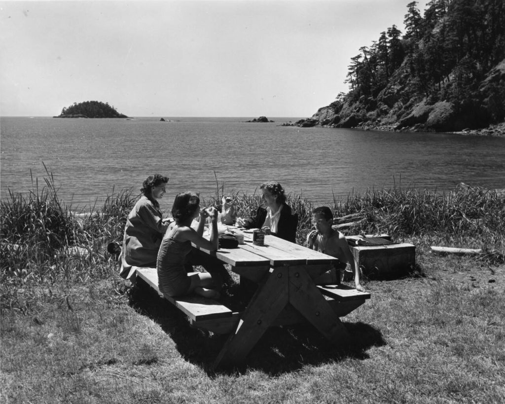 A family enjoys a picnic at Bowman Bay in Deception Pass State Park, circa 1960. (Washington Department of Commerce and Economic Development)
