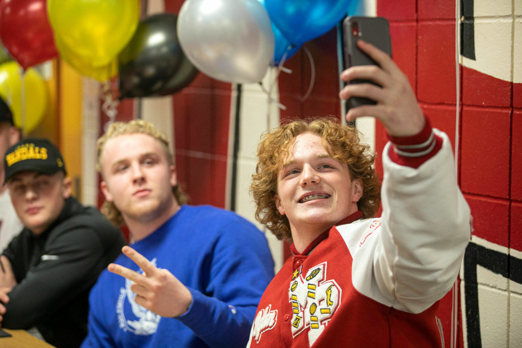 Dylan Carson takes a selfie with Nate Elwood and Jordan Velasquez during National Signing Day Wednesday, Feb. 2, 2022, at Marysville Pilchuck High School in Marysville, Washington. (Ryan Berry / The Herald)
