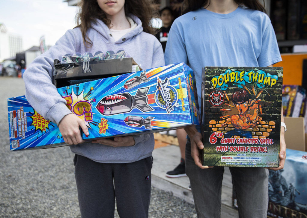 People carry around large boxes of fireworks purchased at Boom City on Thursday in Tulalip. (Olivia Vanni / The Herald)

