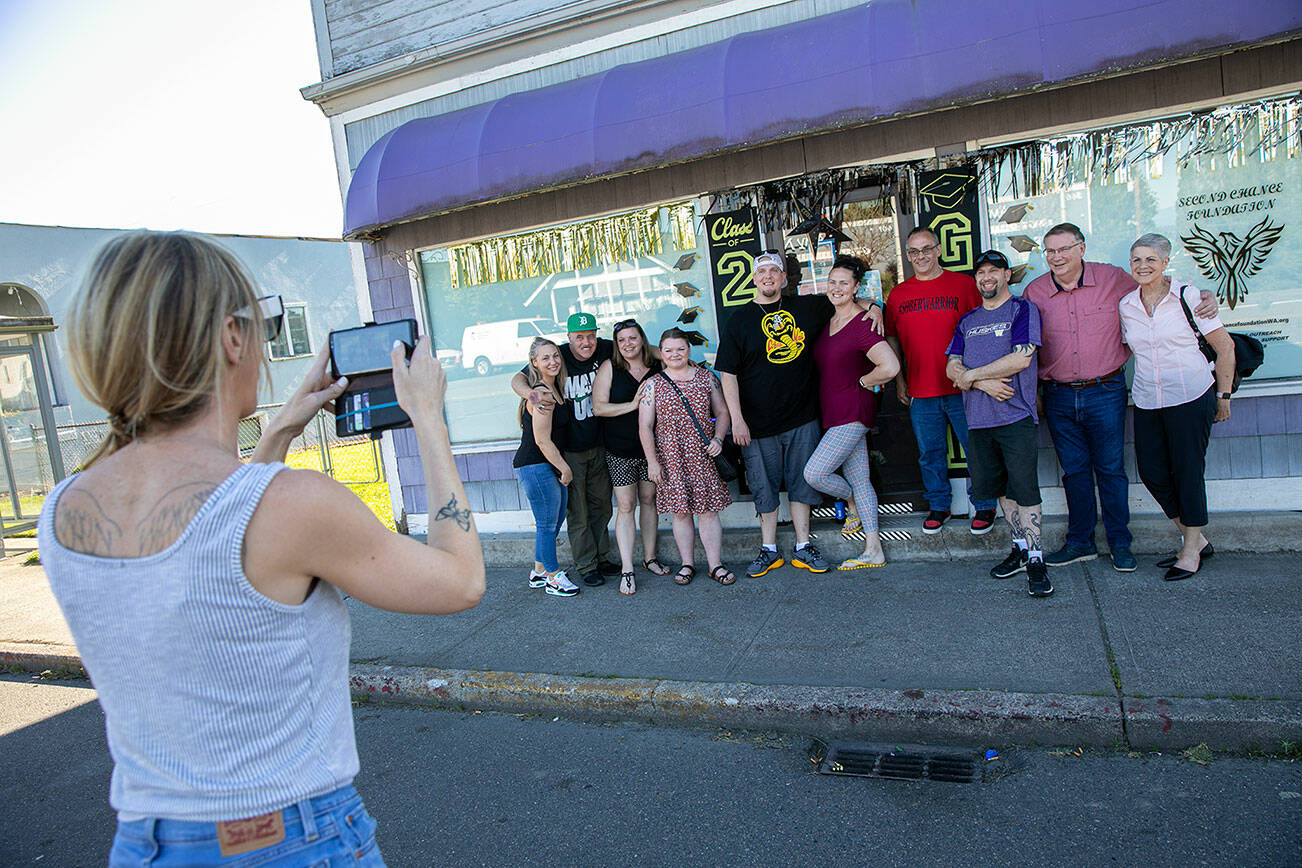 Alissa Long gets a group photo of some of the graduates during a Second Chance Foundation graduation party on Sunday, June 26, 2022, in Everett, Washington. (Ryan Berry / The Herald)