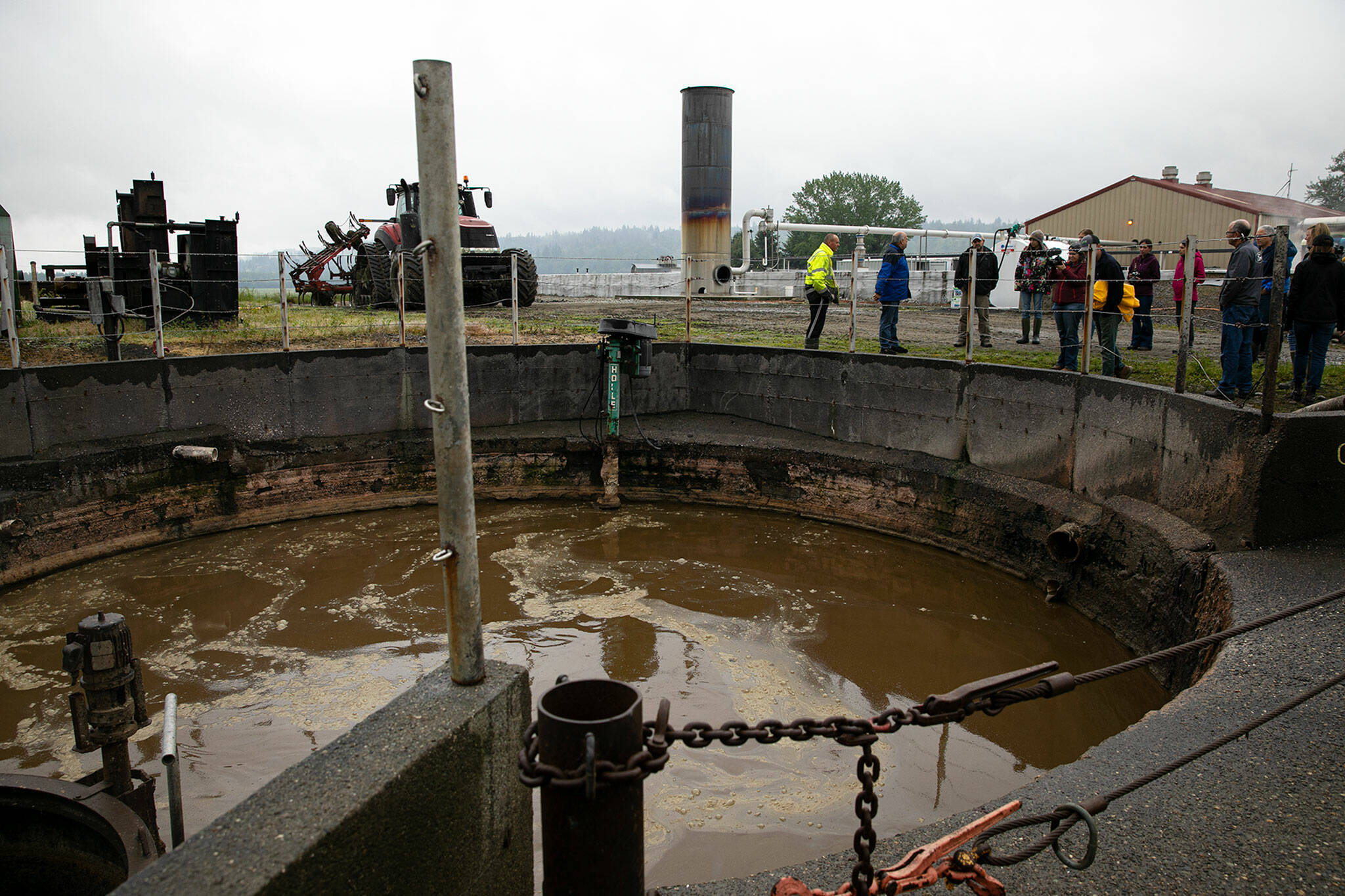 A group gathers near a blending pit, which is where cow waste and other biodegradable material begins its journey towards becoming energy in a digester on June 17 in Monroe. (Ryan Berry / The Herald)