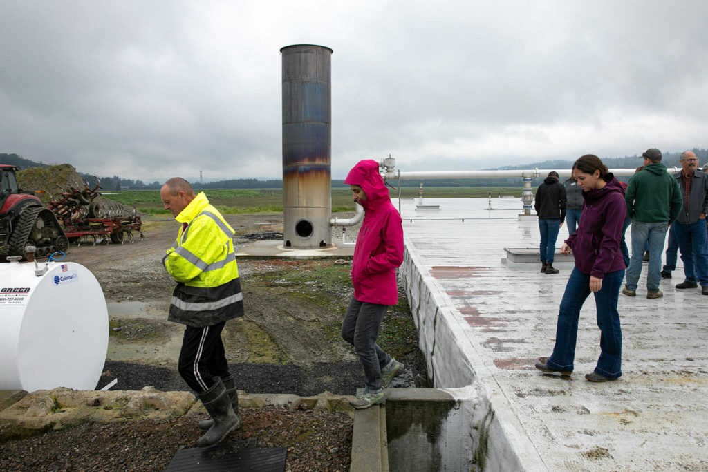 People walk off of the top of the anaerobic digester at Werkhoven Dairy while touring the facility on June 17 in Monroe. (Ryan Berry / The Herald)
