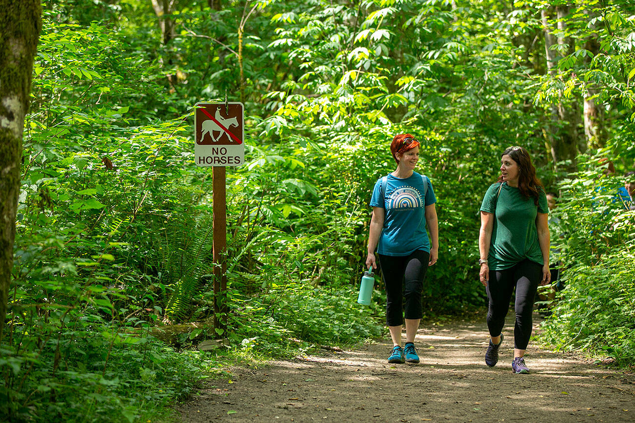 A group of hikers pass by a “no horses” sign on one of the trails at Lord Hill Park on Friday, July 8, 2022, near Snohomish, Washington. (Ryan Berry / The Herald)